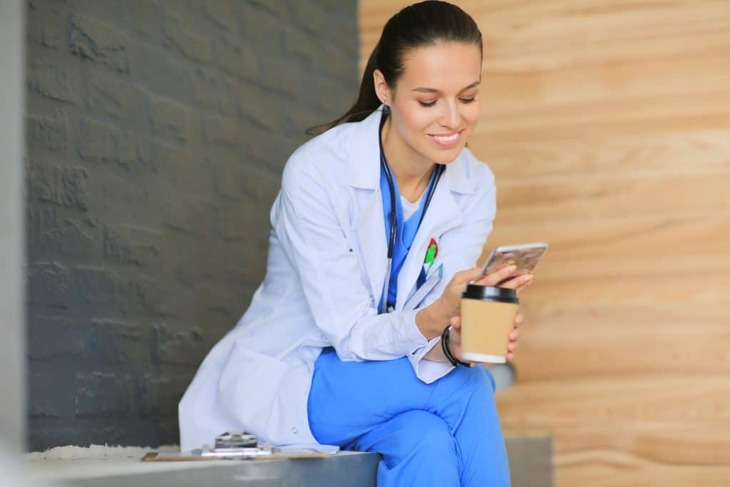 Young woman doctor sitting with your phone. Woman doctors.